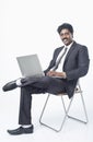 South Indian businessman sitting on a chair and using a laptop Royalty Free Stock Photo
