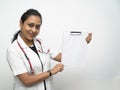 A south Indian female doctor in 30s showing a blank white prescription board white coat and red stethoscope in white
