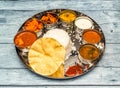 south indian fish meal thali tikka masala, curry, rice, raita, korma, kesari halwa and chapati served in dish isolated on wooden