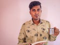 South Indian handsome man holding a book and silver cup in his hands