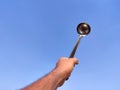 South Indian man hand holding silver laddle .