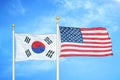 South Korea and United States two flags on flagpoles and blue cloudy sky