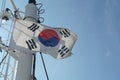 South Korean flag flapping on white mast of a merchant container ship with red and white navigational lights.