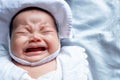 Southeast Asian baby colic is wearing white hat and shirt. South East Asian newborn is crying. Newborn is unhealthy. Royalty Free Stock Photo