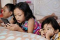 Southeast Asian ethnicity little boy feeling bored while his two big sister focus playing their smartphone Royalty Free Stock Photo