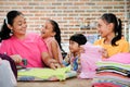 Southeast Asian Family Domestic Lifestyle: Stay at home mother happy ironing clothes surrounded by her three children Royalty Free Stock Photo