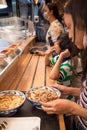 Southeast Asian family, mother and two children ordering dinner in Japanese restaurant with udon menu