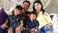 Southeast Asian family spending time at home. Happy Indonesian or malasian parents and children laying in bed having fun