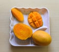 Southeast Asian fruit, fresh hedgehog style Mango preparation, cubes and chunks on white plate, isolated on a white background.