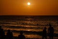 Southern orange scarlet sunset with a large sun on the surface of the water in the tropical sea. Black silhouette of fishing boat