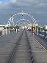 The historic pier in southport merseyside with people walking towards the town and the suspension bridge and buildings visible beh