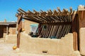 Southwestern US Adobe dwelling with pole ramada sunshade over patio and painted details in turquoise with pumpkins sitting around