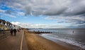 Southwold`s iconic beach huts and pier against a dramatic sky in Southwold, Suffolk, UK