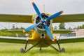 Soviet aircraft biplane Antonov AN-2 with blue four blade propeller and yellow fuselage parked on a green grass of airfield Royalty Free Stock Photo