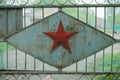 Soviet military five-pointed star on the green scuffed gate. Abandoned restricted zone