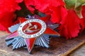 Soviet order of Patriotic War inscription Patriotic war with red carnations on an old wooden table. May 9 day of victory in the Royalty Free Stock Photo