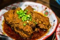 Soy Bean Sauce Pork Ribs with chopped shallots in a porcelain dish