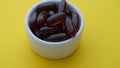 Soy lecithin softgels in a white bowl on a yellow background