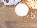 Soy milk in a glass and sackcloth bag on a brown wood background. Top view with copy space. Plant protein. Royalty Free Stock Photo