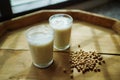 Soy milk homemade in glass cup decorated by soybean on wooden table background.
