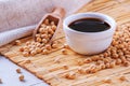 Soy sauce with soya beans scattered on a bamboo napkin against the background of burlap