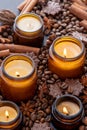 Soy scented candle in a jar. Coffee beans, anise, cinnamon spices. The candles are burning. Dark background.