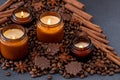 Soy scented candle in a jar. Coffee beans, anise, cinnamon spices. The candles are burning. Dark background.