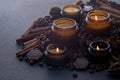 Soy scented candle in a jar. Coffee beans, anise, cinnamon spices. The candles are burning. Dark background.