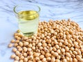 Soybean oil in a glass placed beside the soybean seed stack on a white background