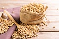 Soybean seeds in a sack with wooden spoon, placed on a wooden table, natural healthy food - top view