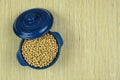 Soybeans in blue bowl on a straw background. Protein pulse that is dried and then soaked and cooked before eating. Top view. Royalty Free Stock Photo