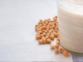 Soybeans and glass of soymilk on a white fabric background.
