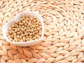 Soybeans in a heart-shaped bowl on rattan bamboo mat.