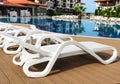 White plastic chaise lounges by the pool. Close-up. Royalty Free Stock Photo