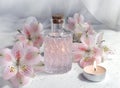 Spa aromatherapy concept with perfume glass or aroma oil glass, flowers and candle on light background.