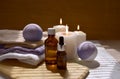 Spa aromatherapy still life with aroma oil bottle, purple bath bombs and lit candles. Royalty Free Stock Photo