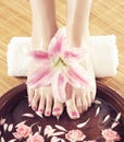 Beautiful legs, flowers, petals and ceramic bowl. Summer spa background.