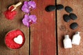 Spa background with orchid, red salt for coconut baths, body lotions and stones for hot massage on a wooden table with Royalty Free Stock Photo