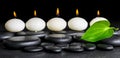 Spa background of row white candles and green leaf on black zen Royalty Free Stock Photo