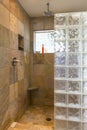 Spa bathroom shower area with stone tile and glass block walls in contemporary upscale home interior