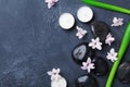 Spa beauty background with massage pebble, green leaves, flowers and candles on black stone table top view. Aromatherapy. Royalty Free Stock Photo