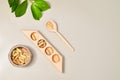 Herb in capsules in wooden bowl on pastel beige background. Beauty products for face and body skin care