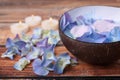 Spa composition. Aromatic water in bowl, burning candles and flowers on wooden table, closeup. Space for text Royalty Free Stock Photo