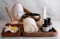 Spa composition with Buddha head, singing bowl, herb massage bag, sea salt and aroma oil on wooden tray on marble wall background Royalty Free Stock Photo