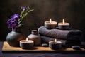 Spa composition with purple orchids, candles, towels, and stones on a wooden stand against a dark background Royalty Free Stock Photo