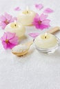 Spa composition with sea salt bath in wooden spoon, pink flowers and burning candles Royalty Free Stock Photo