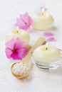 Spa composition with sea salt bath in wooden spoon, pink flowers and burning candles on a white surface Royalty Free Stock Photo