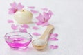 Spa composition with sea salt bath in wooden spoon, pink flowers petals and burning candle on a white surface Royalty Free Stock Photo