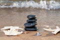 Spa composition - stacked Basalt Stones, Seashells and Sea Stars on the beach at sunrise in front of the ocean. Royalty Free Stock Photo