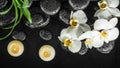 Spa composition white orchid phalaenopsis, candles and black zen stones with drops in water, panorama Royalty Free Stock Photo